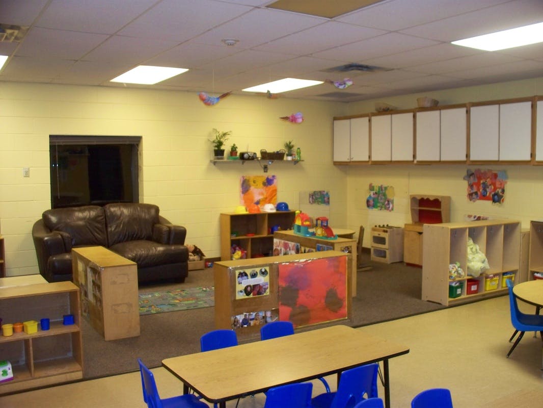 Classroom with small tables and chairs, shelves, and a brown sofa