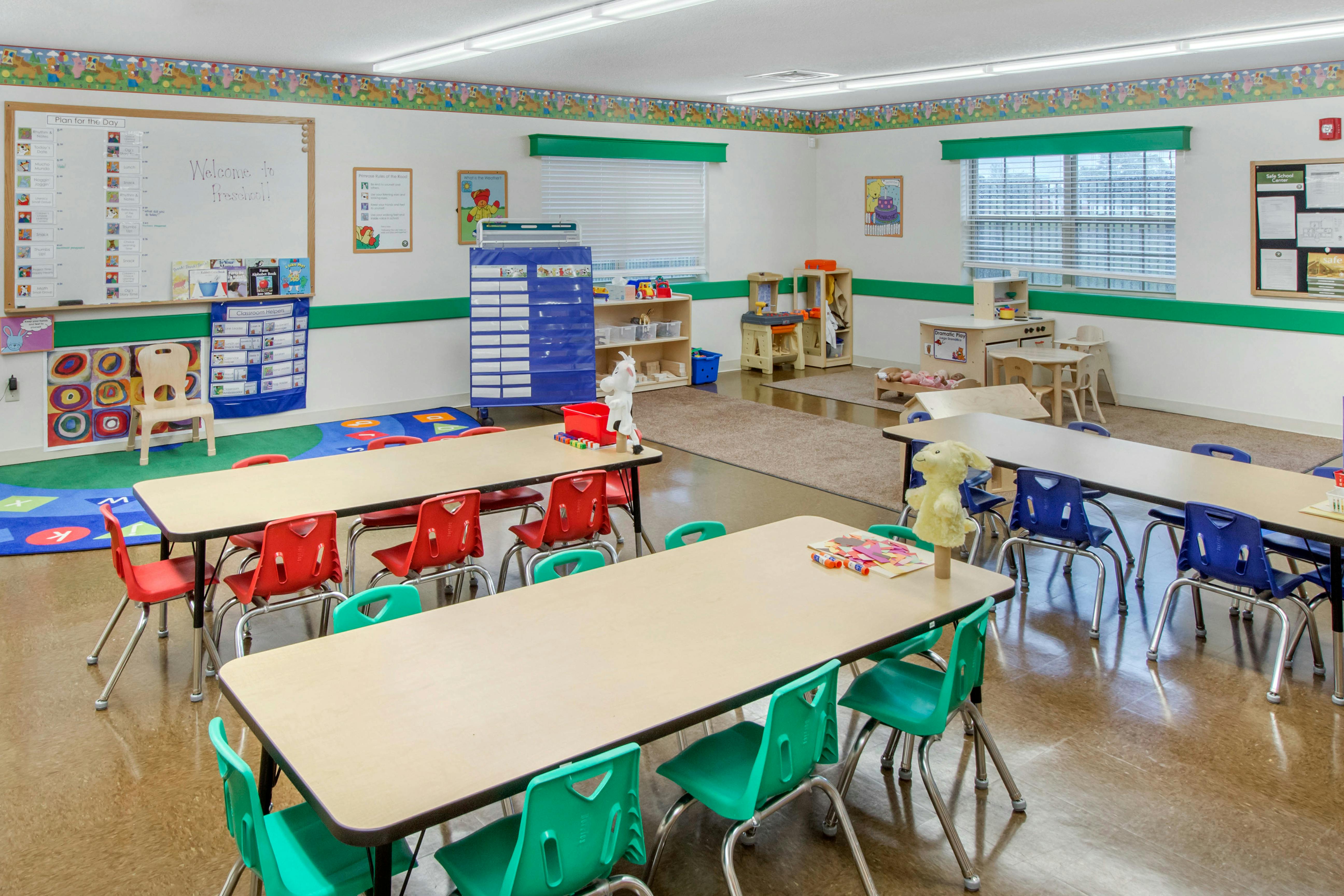 Empty preschool classroom with small tables and chairs, play areas