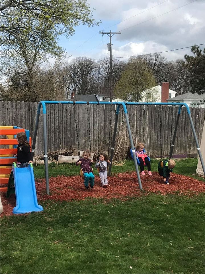 Children playing on a swing set and slide in a backyard
