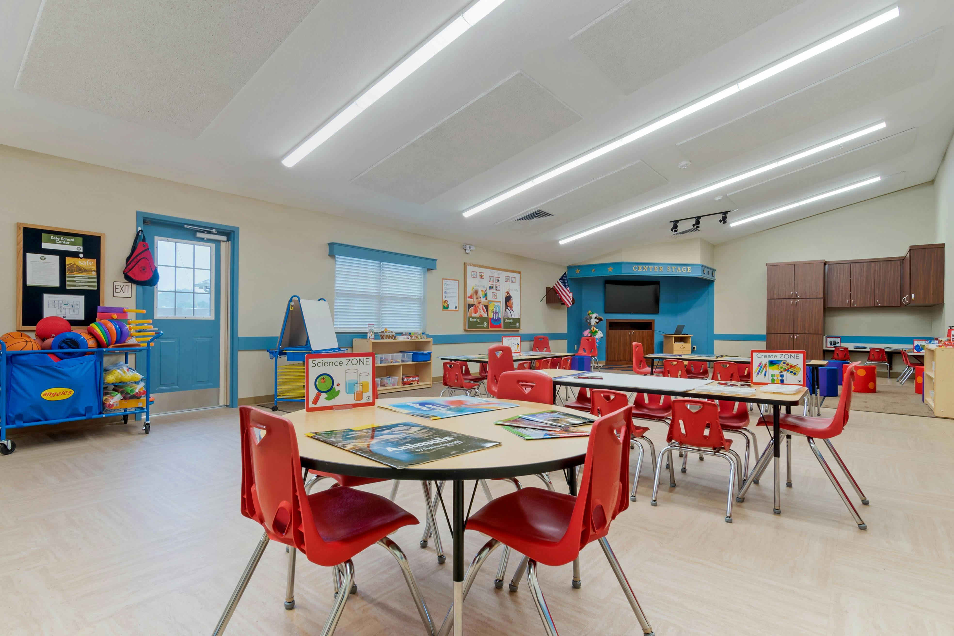 Classroom with tables and red chairs, a science zone sign on a table