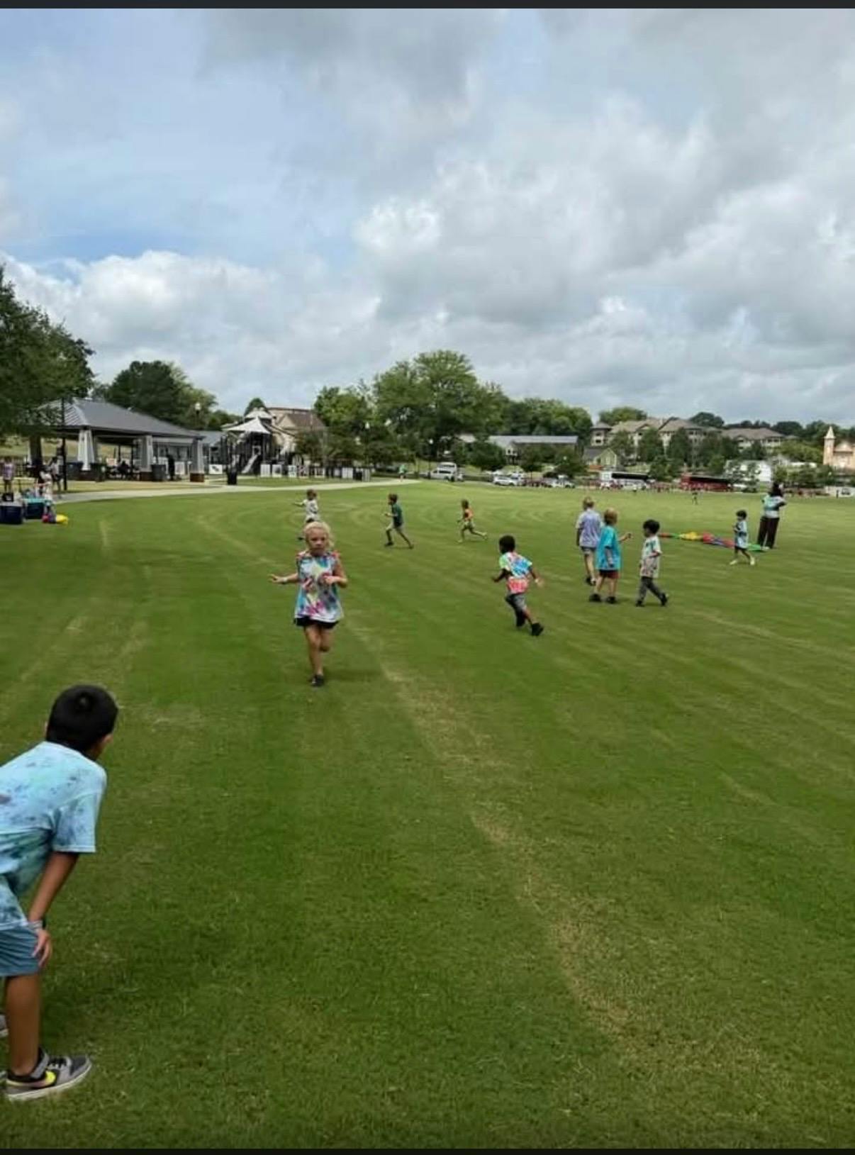 Children running across a grassy park field