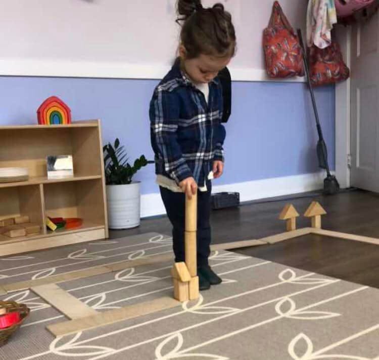Child playing with wooden blocks on a rug
