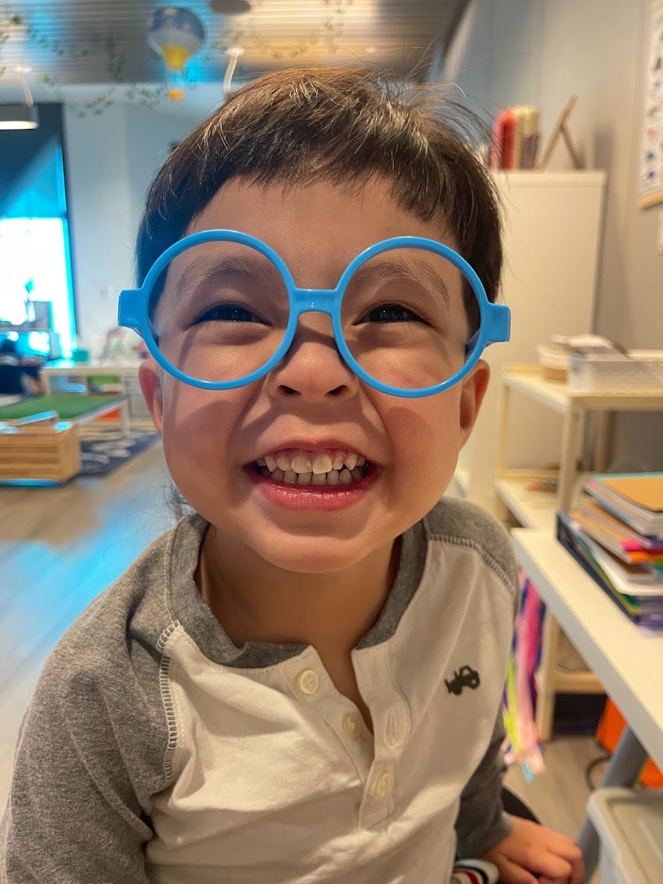 Child wearing blue round glasses and smiling