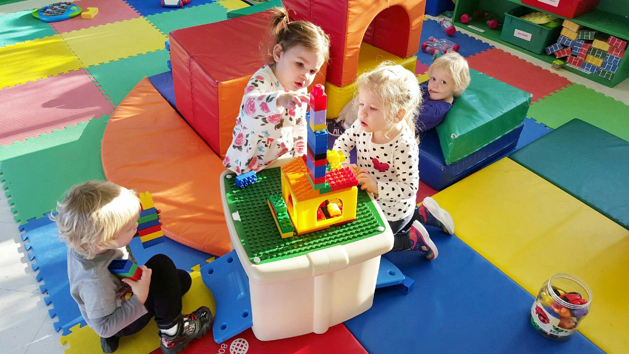Children playing with building blocks on a colorful mat