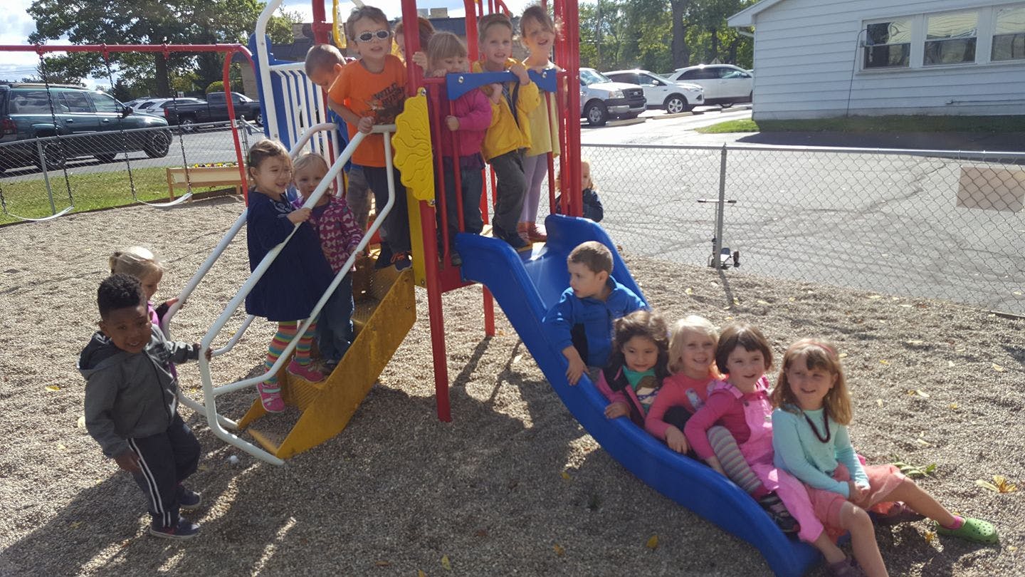 Children playing on a playground structure with a slide and swings