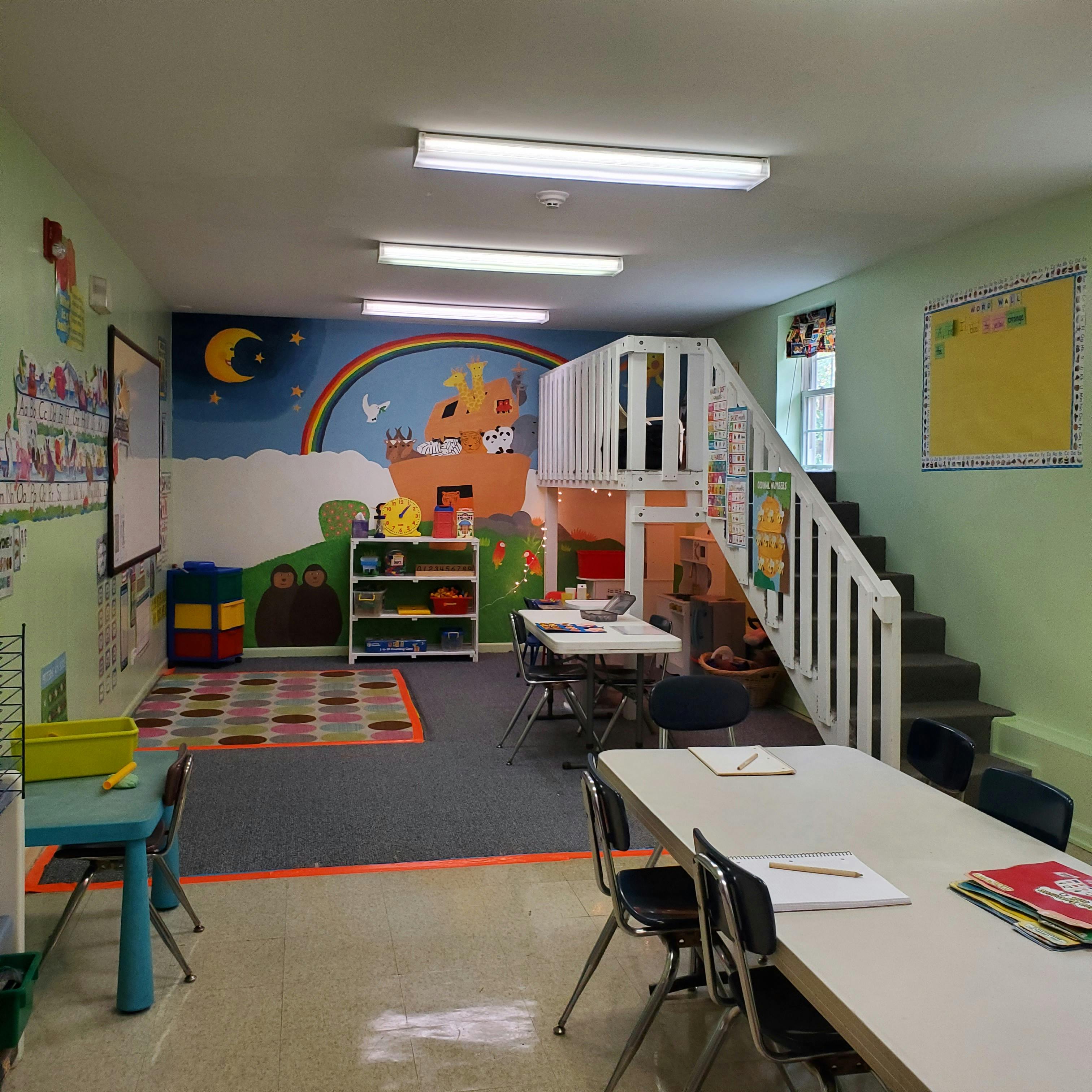 Classroom with tables, chairs, play structure, and colorful mural