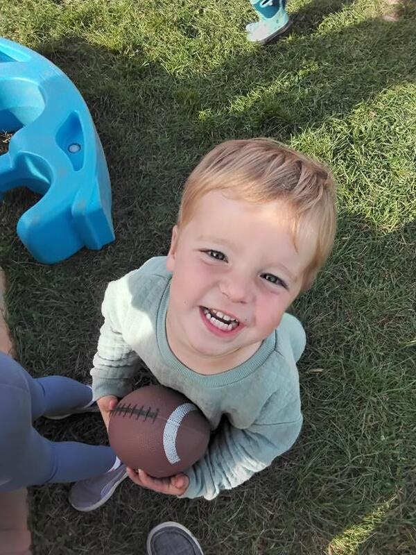 Child holding a football on grass