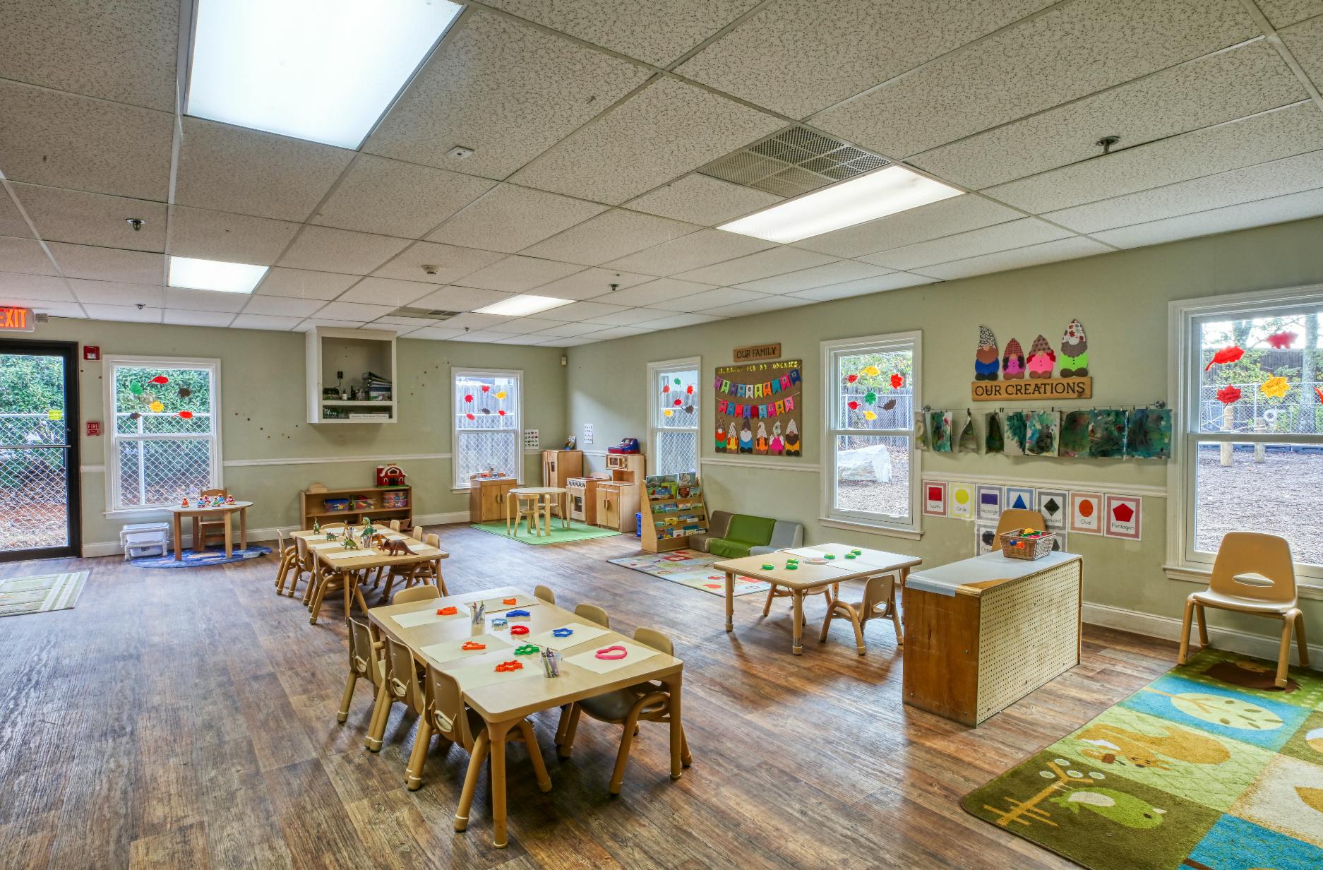 A classroom with small tables and chairs, and colorful decorations on the walls
