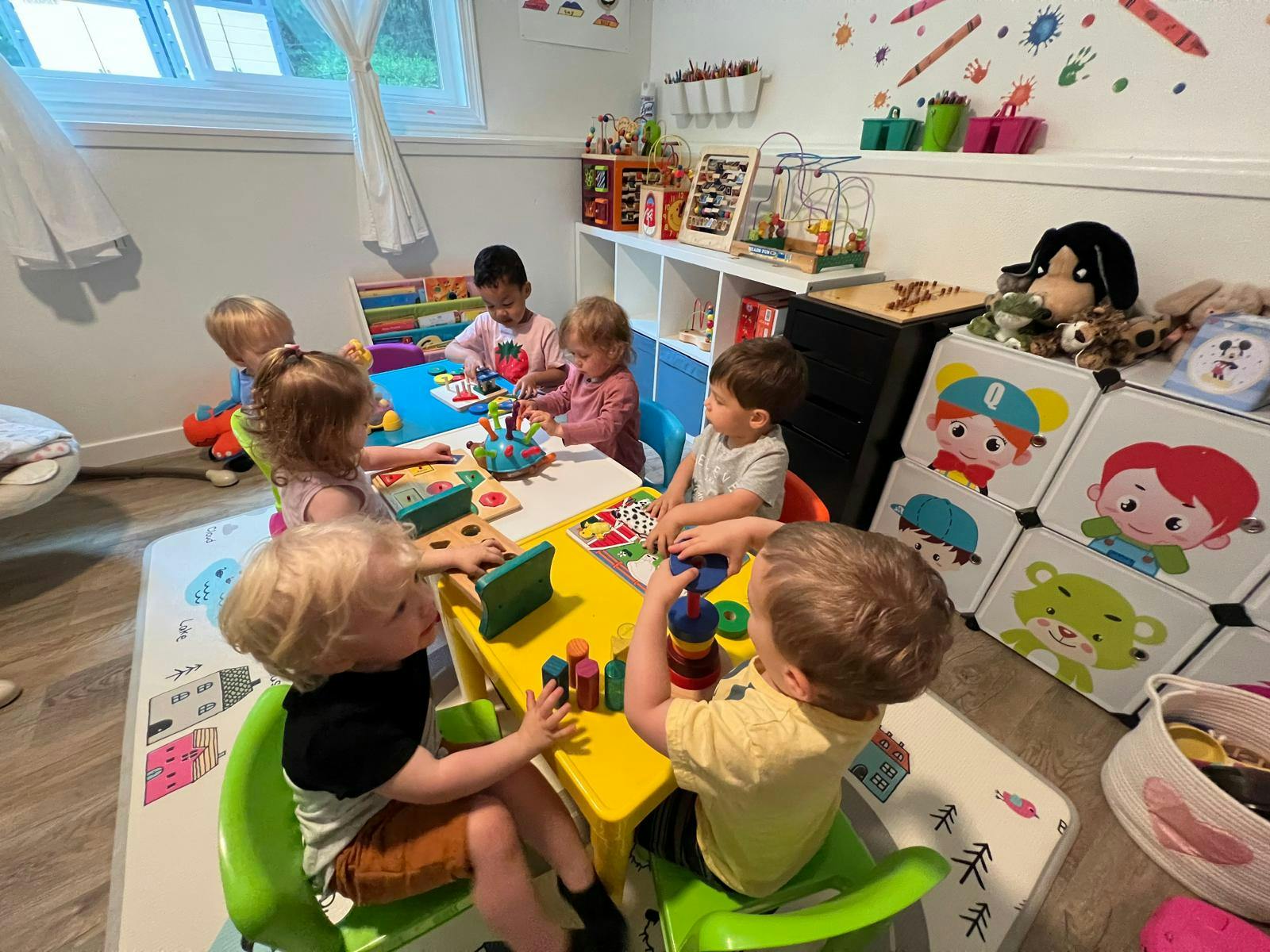 Children playing with toys at small tables in a room