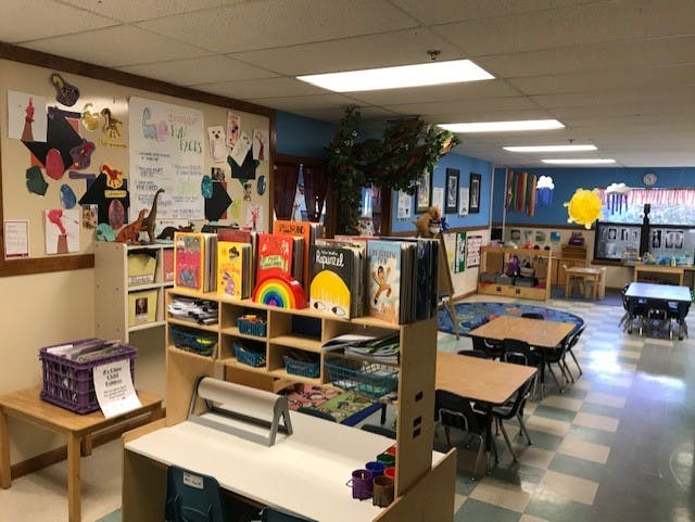 children's classroom with tables, chairs, bookshelves, and colorful wall decorations