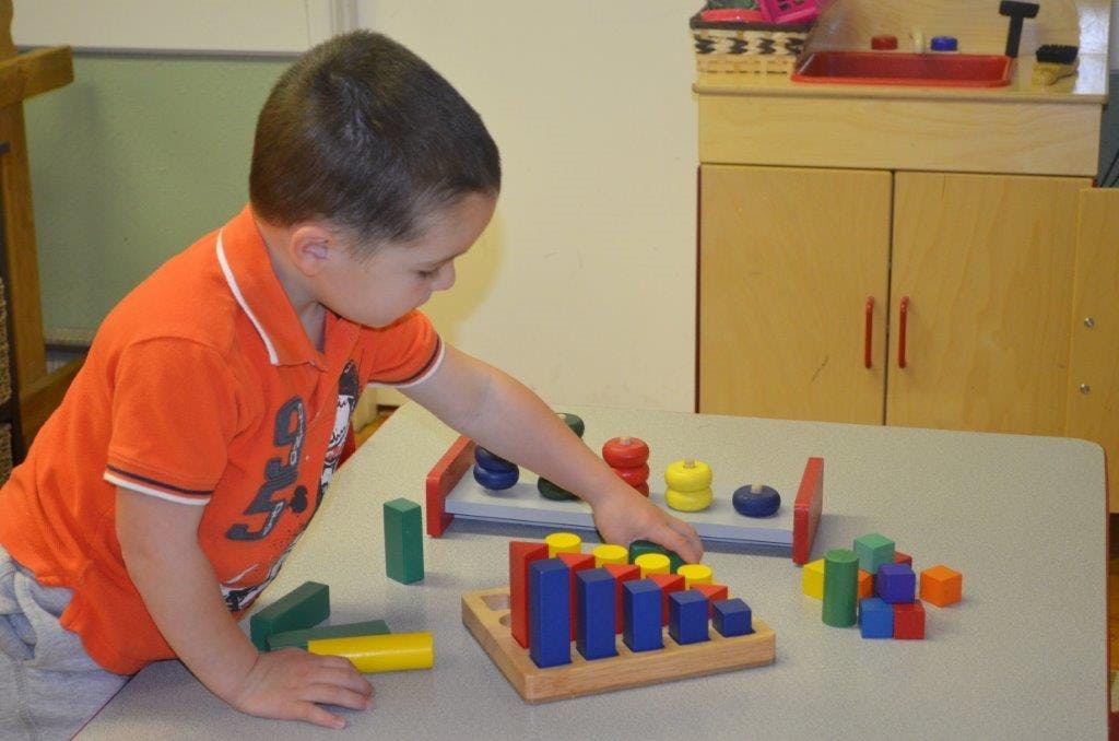 Child playing with colorful wooden blocks and sorting toys on a table