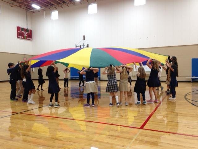Children playing with a colorful parachute in a gymnasium