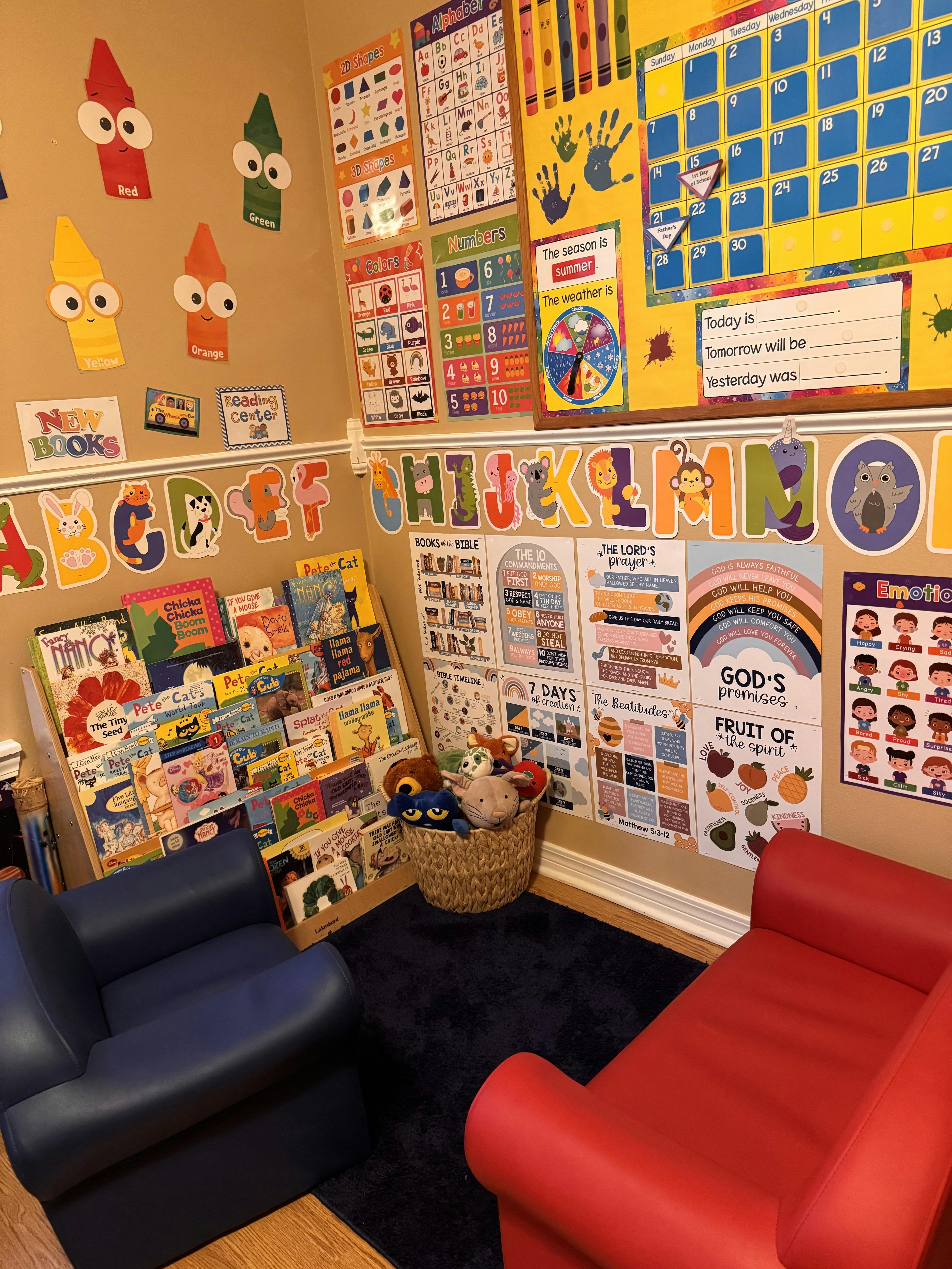 A children's reading nook with a bookshelf, two small armchairs, and wall charts