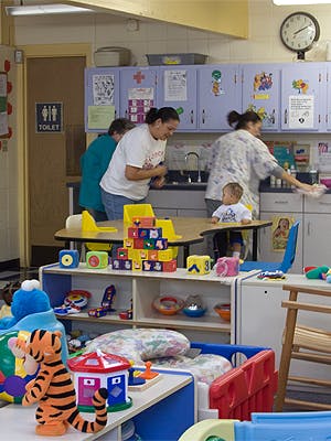 Three people and a child in a room with toys and a sink area