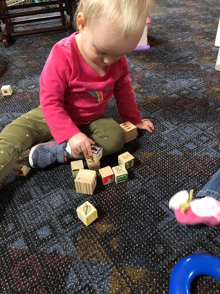 Child playing with wooden blocks on a carpeted floor