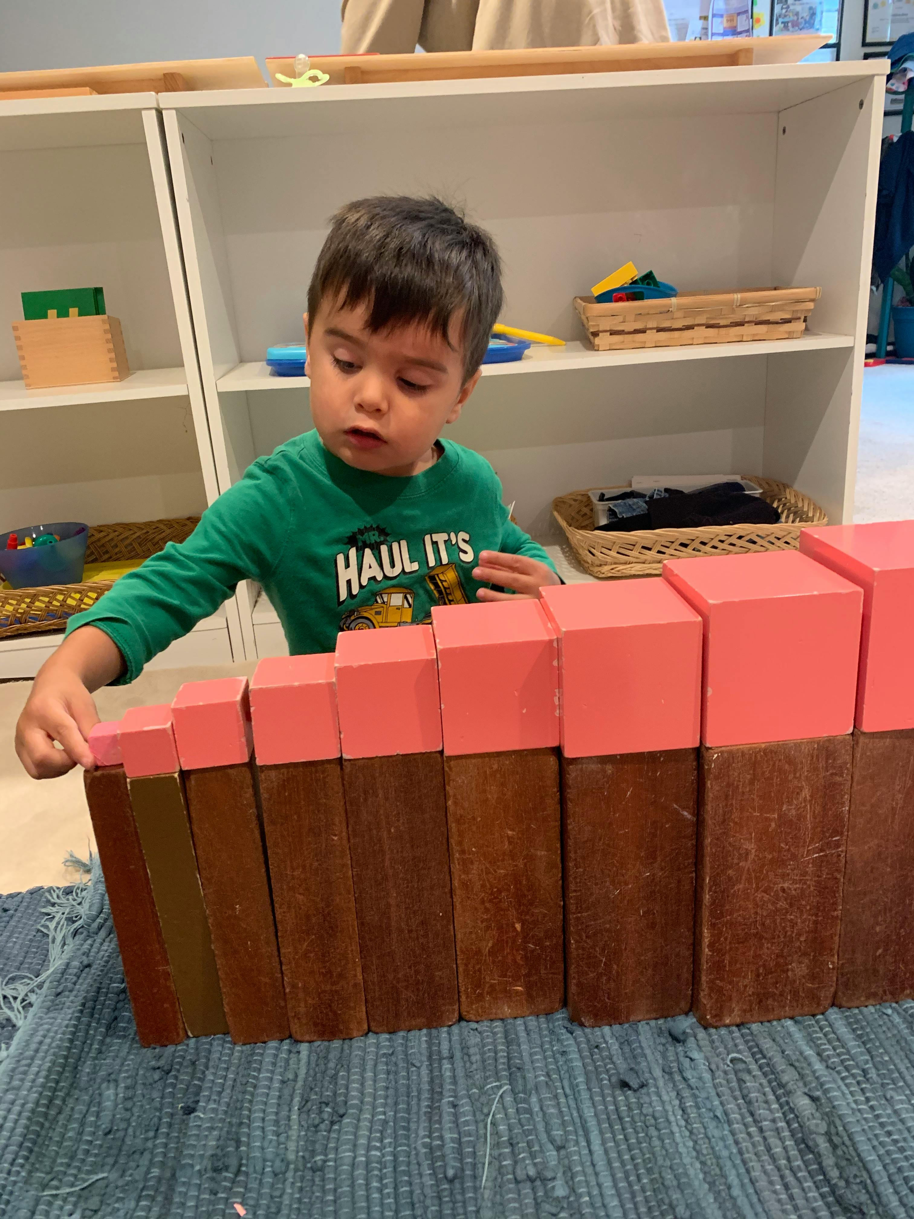 Child playing with pink and brown blocks