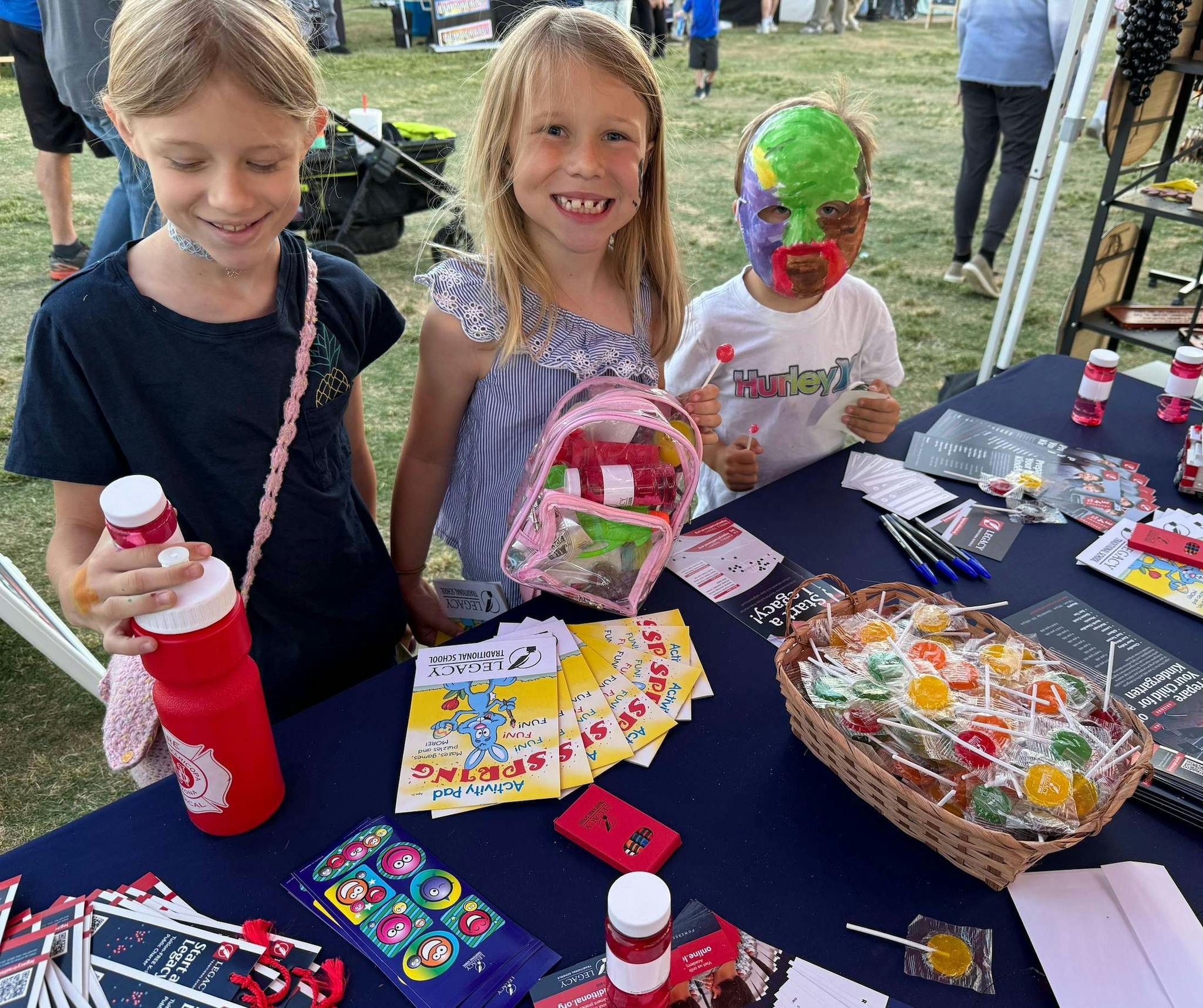 Three children standing behind a table with candy and promotional items