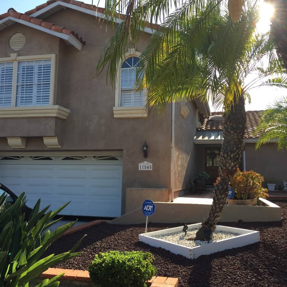 Front exterior of a house with a garage, palm tree, and landscaping