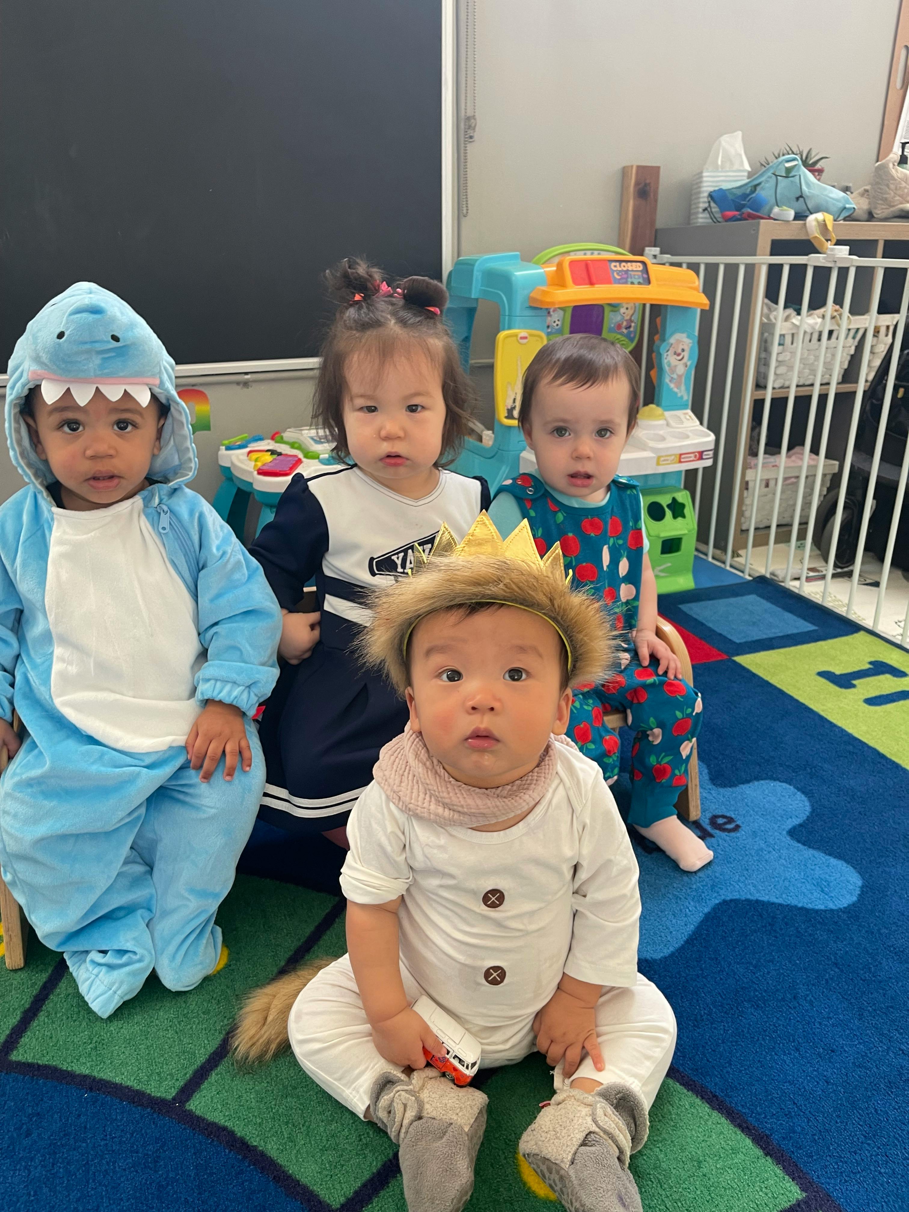 Four children in costumes sitting on a colorful rug