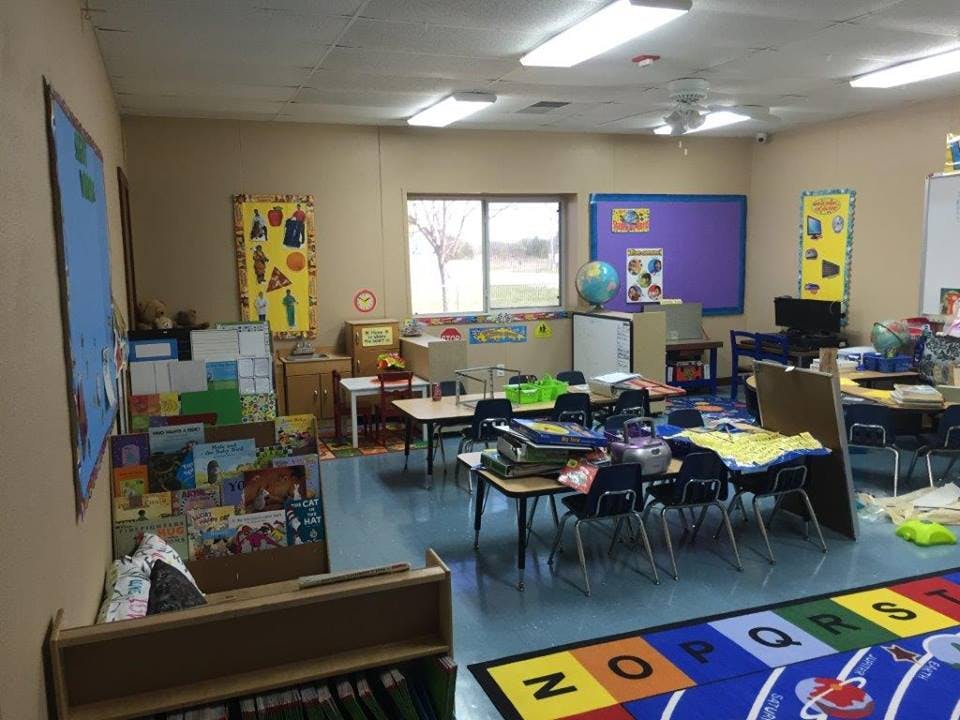 Classroom with small tables and chairs, a window, and educational posters