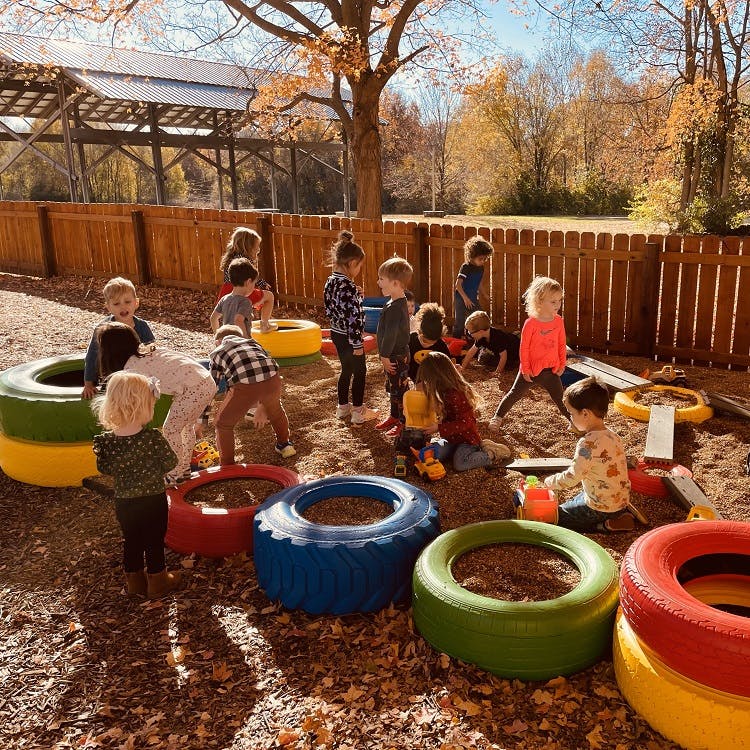 Children playing in a sandbox with colorful tires