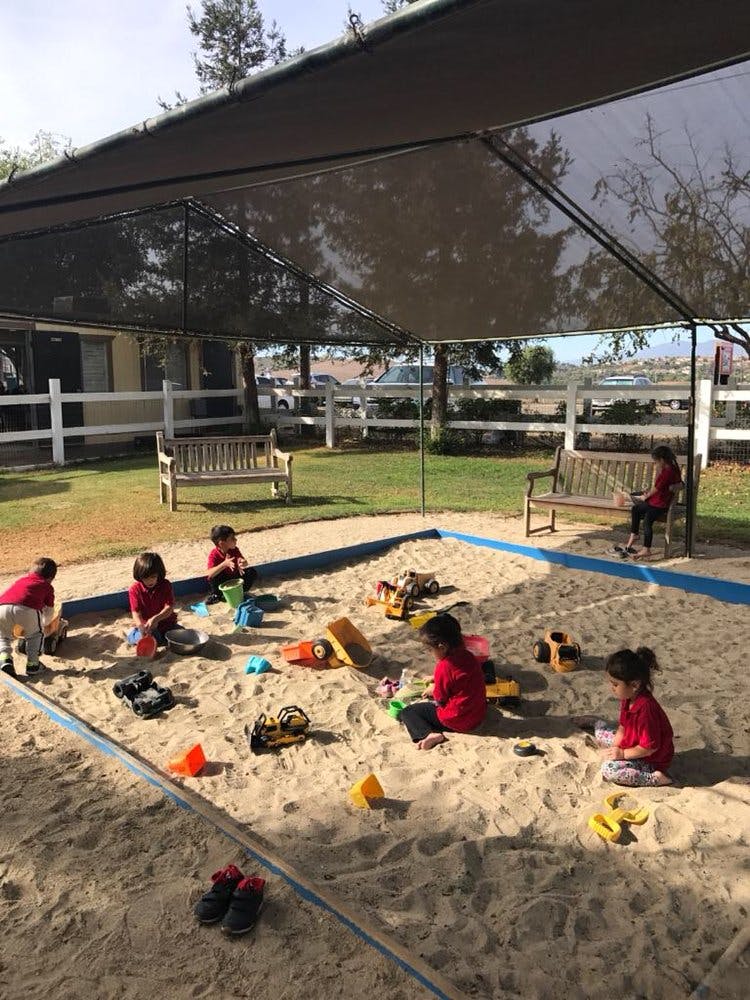 Children playing in a sandbox with toys