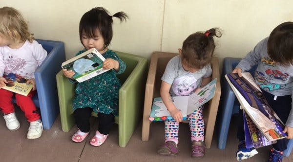 Four children sitting in chairs reading books