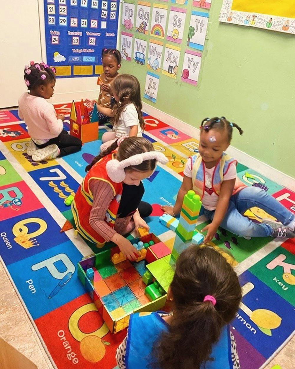 Children playing with blocks on a colorful alphabet rug