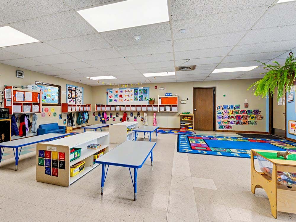 Empty classroom with small tables, storage, and colorful decorations