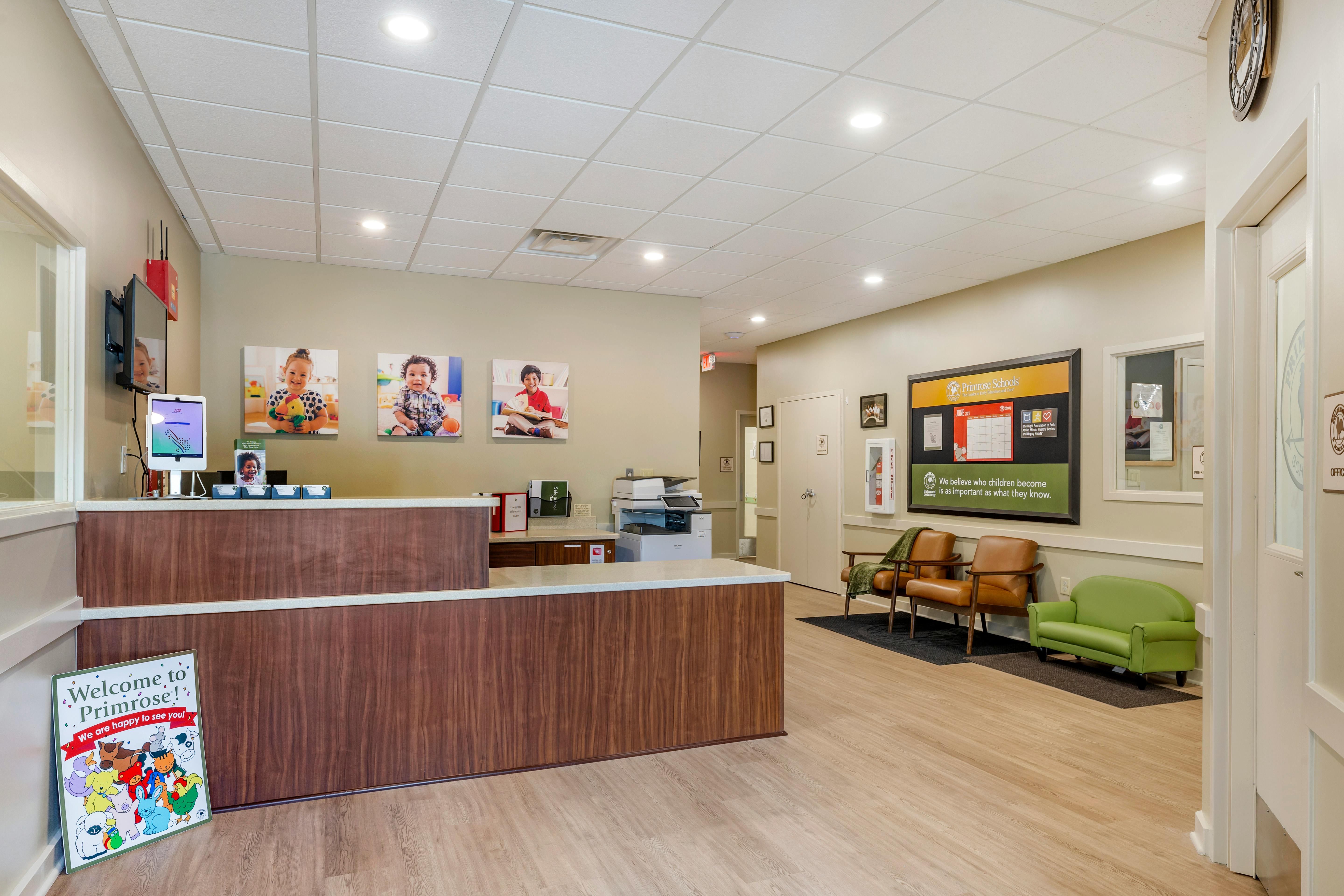 Reception area with a wooden desk, screen, and waiting area seating