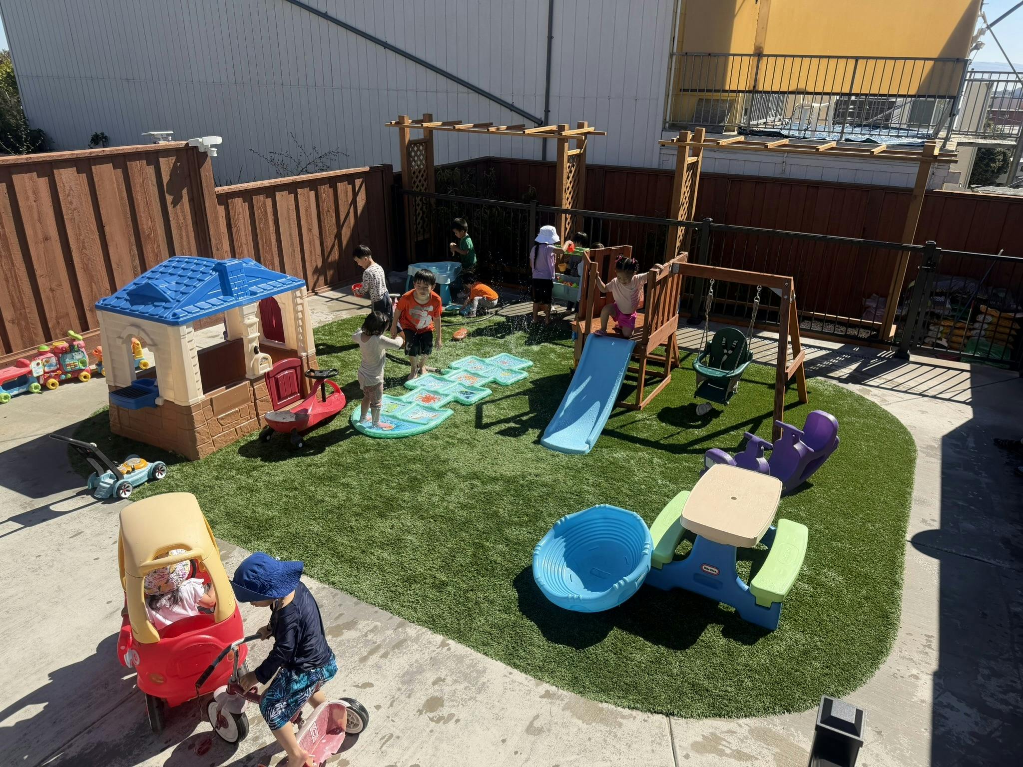 Children playing with water toys and playground equipment in an outdoor yard