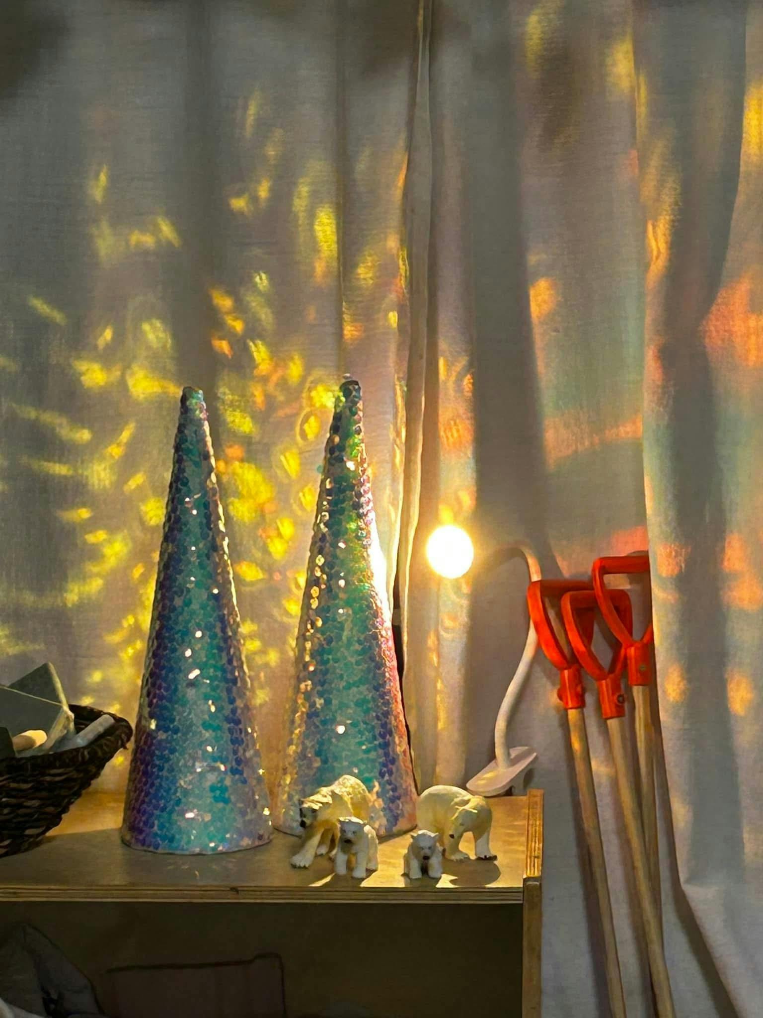 Two cone-shaped decorations and animal figurines on a shelf with light patterns