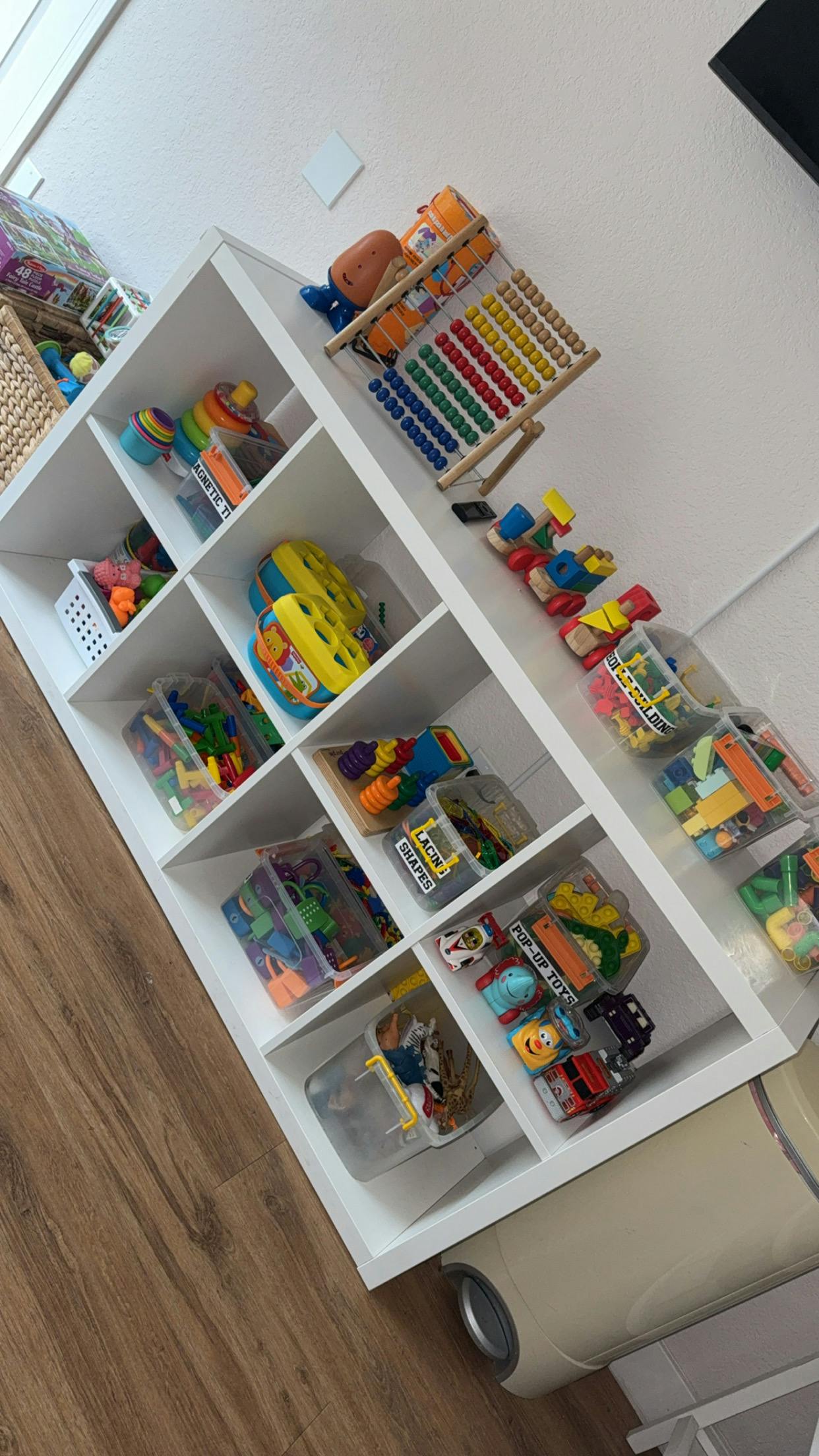 White shelving unit filled with various toys and learning materials