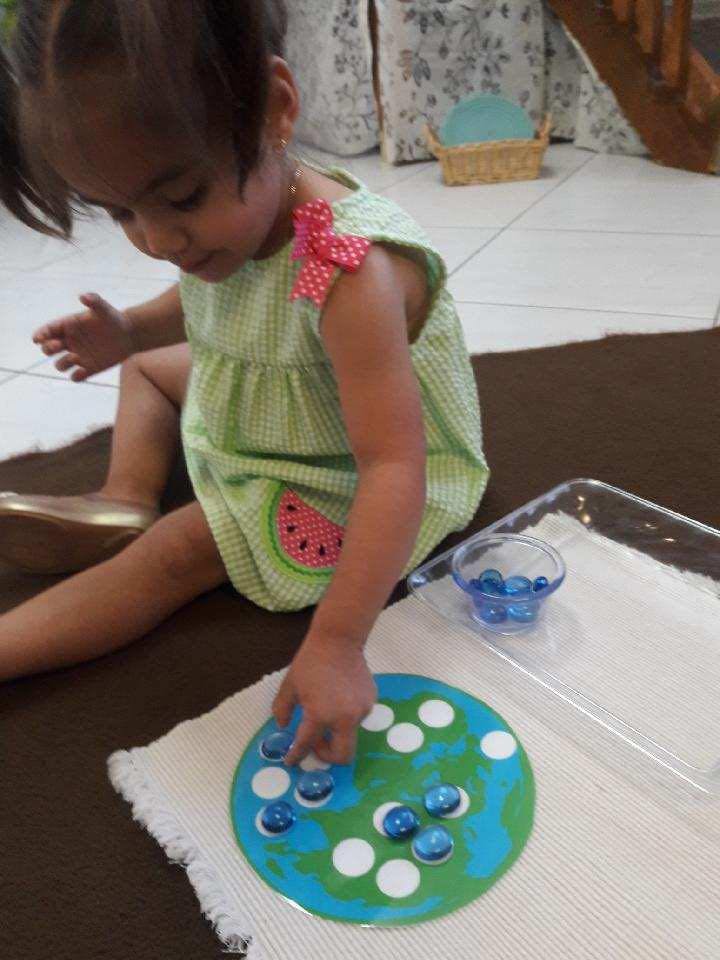 Child placing blue marbles on a round earth-themed board