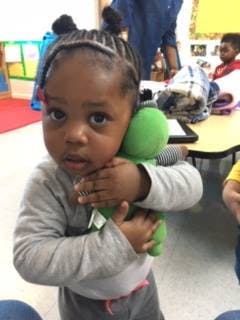Child holding a green stuffed animal