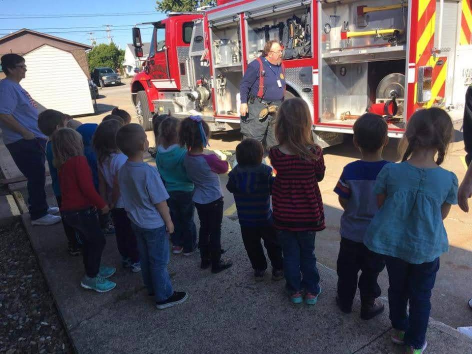 Children and adults standing near a fire truck