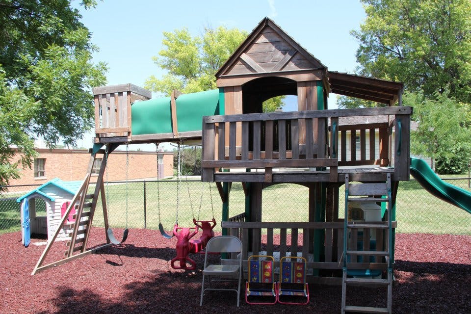 Wooden playground structure with swings and a slide