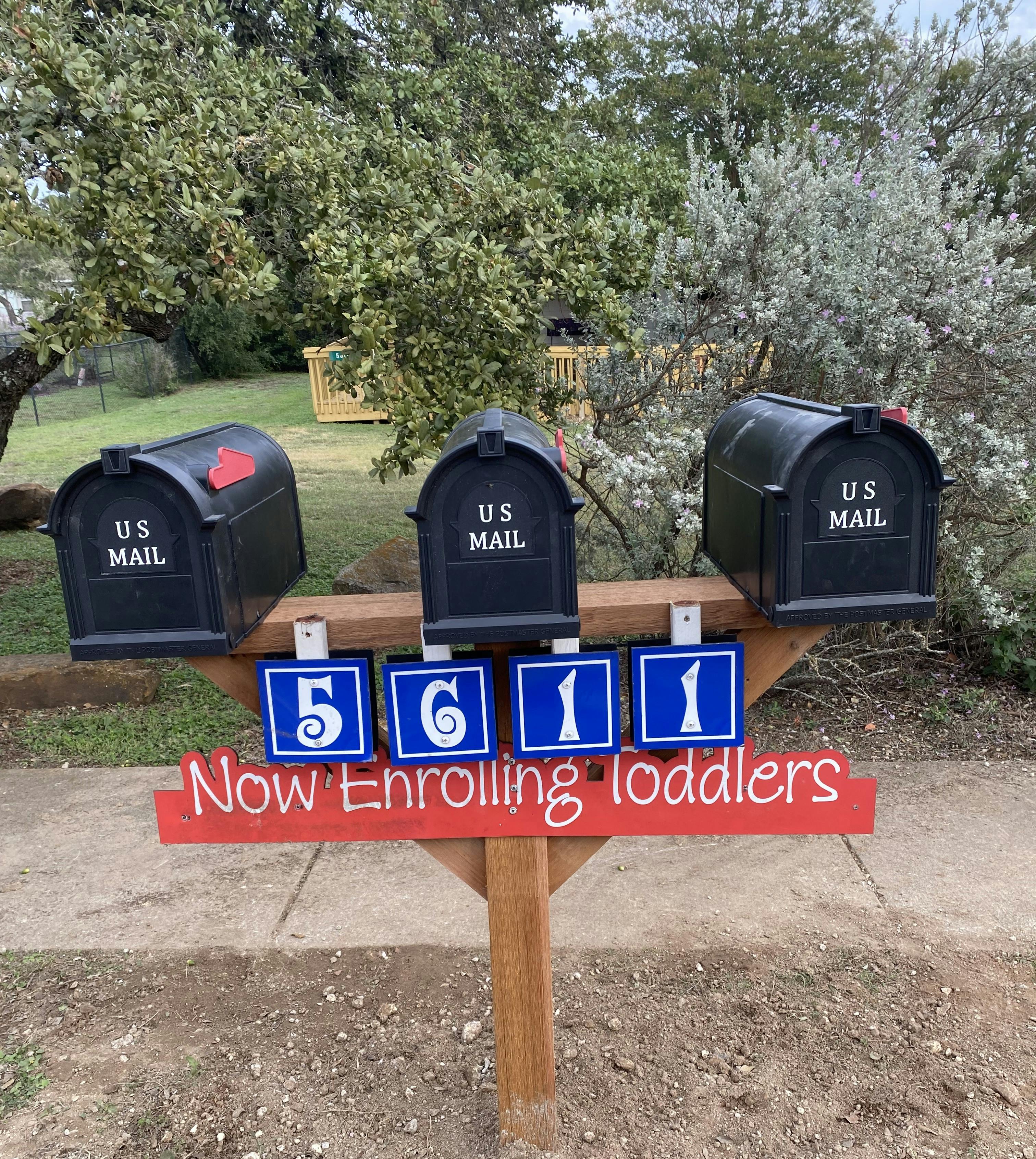 Three mailboxes on a post with a sign that reads "Now Enrolling Toddlers"