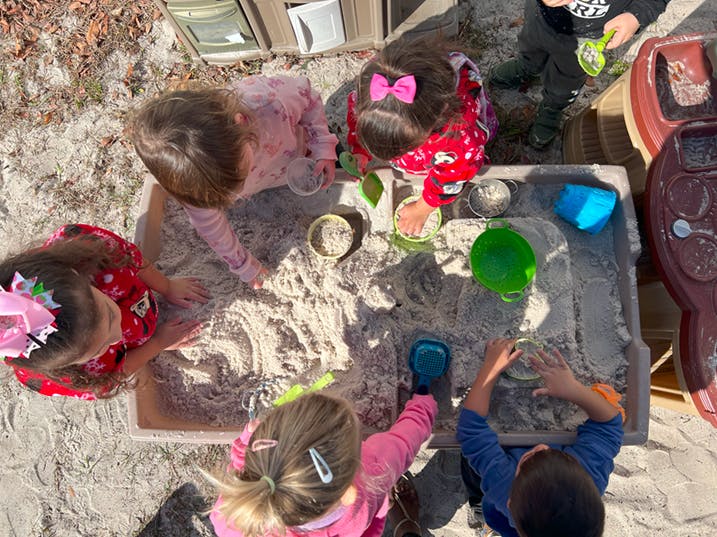 Children playing in a sandbox with sand and toys