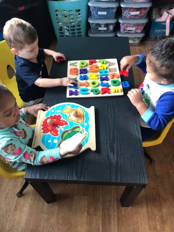 Three children playing with puzzles at a table