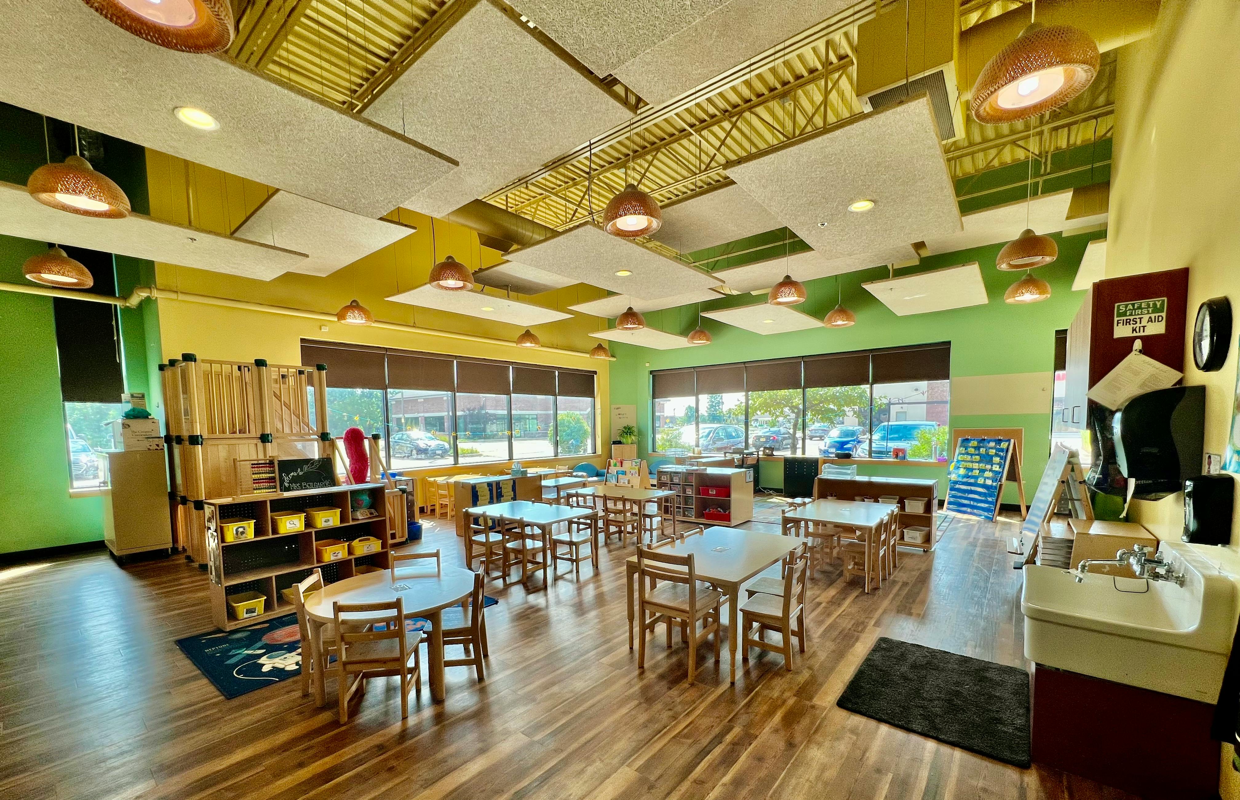 Classroom with small tables and chairs, shelves, and large windows