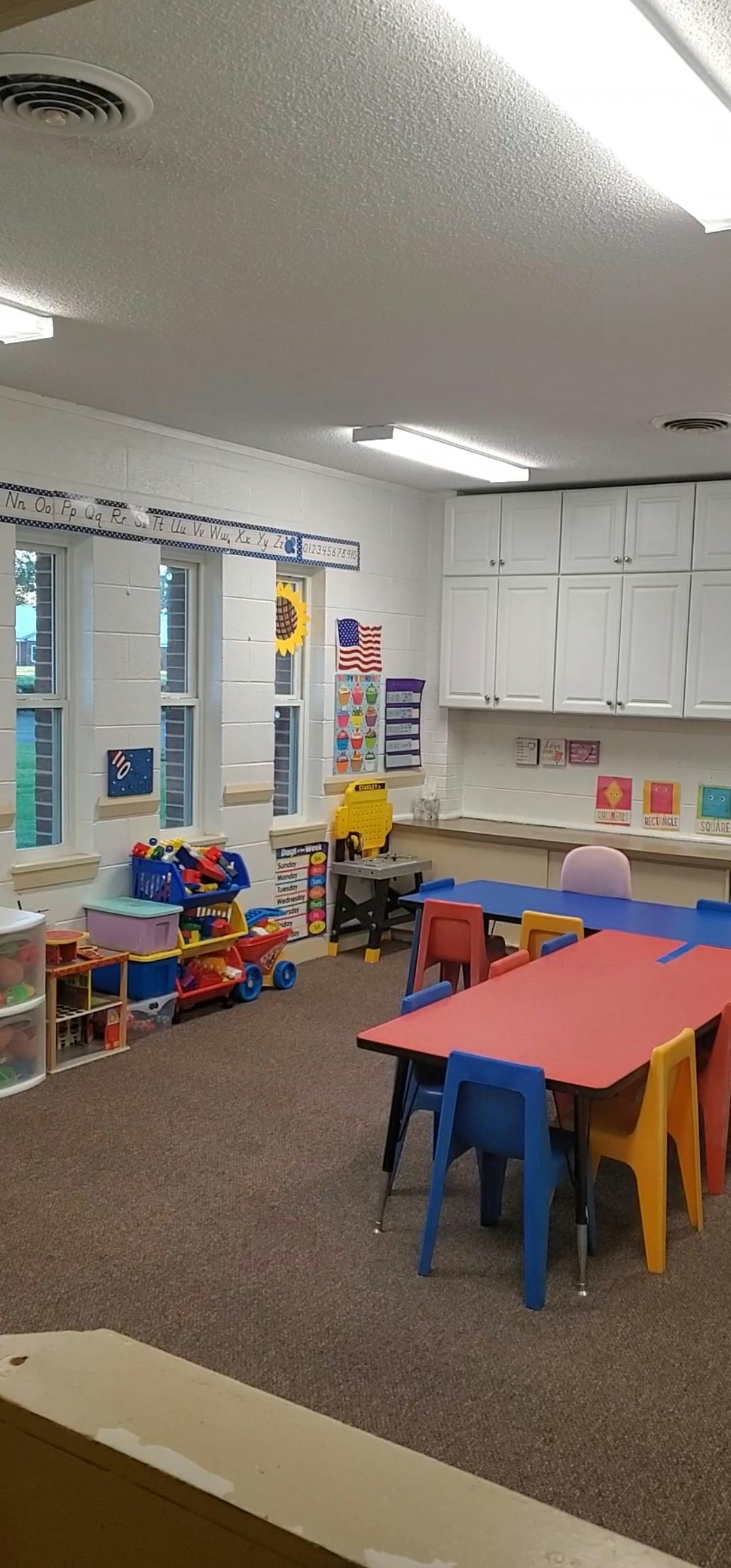 Classroom with colorful tables and chairs, toys, and windows