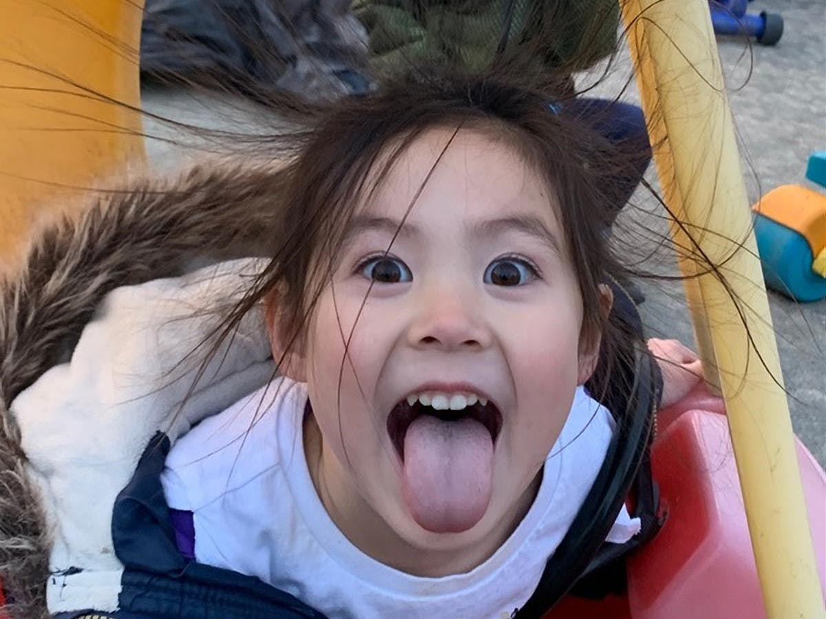 Child with hair standing up, mouth open, and tongue out
