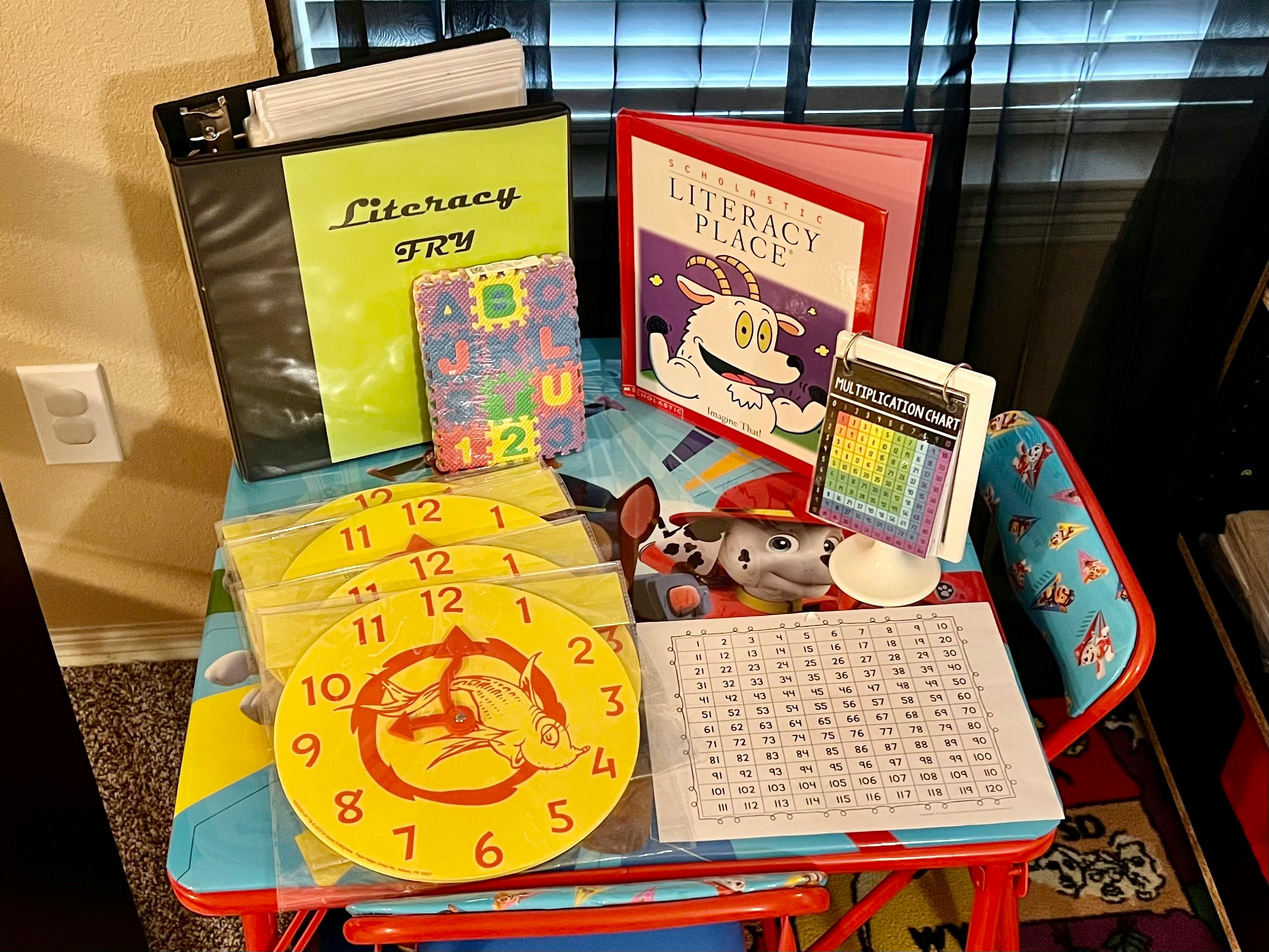 Literacy materials including books, flashcards, and clock faces on a small table