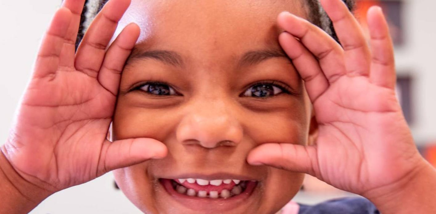 Child with hands framing face