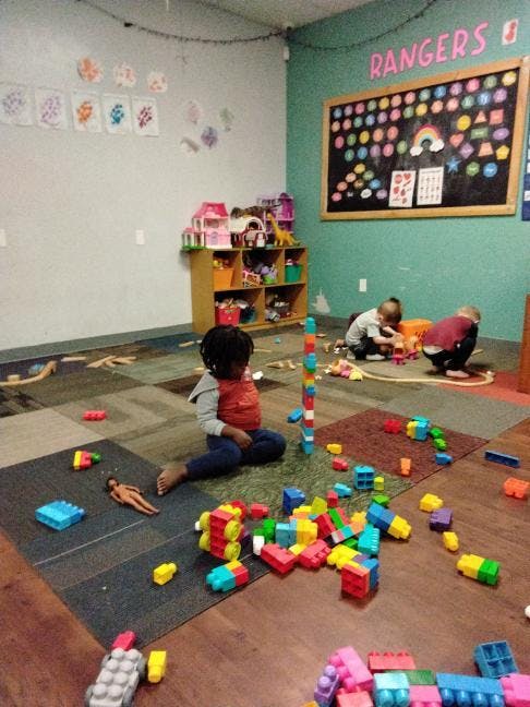 Children playing with blocks and toys on the floor in a classroom