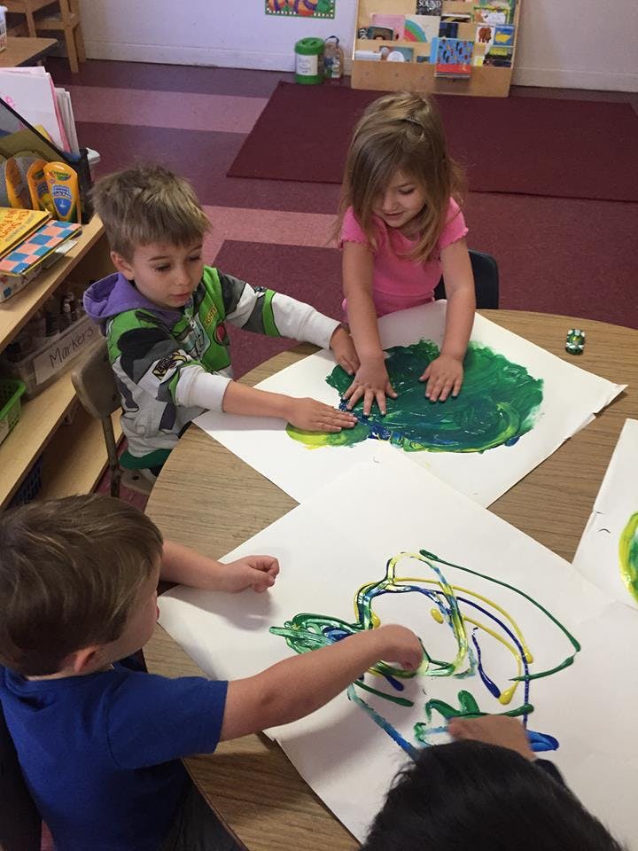 Children finger painting at a table