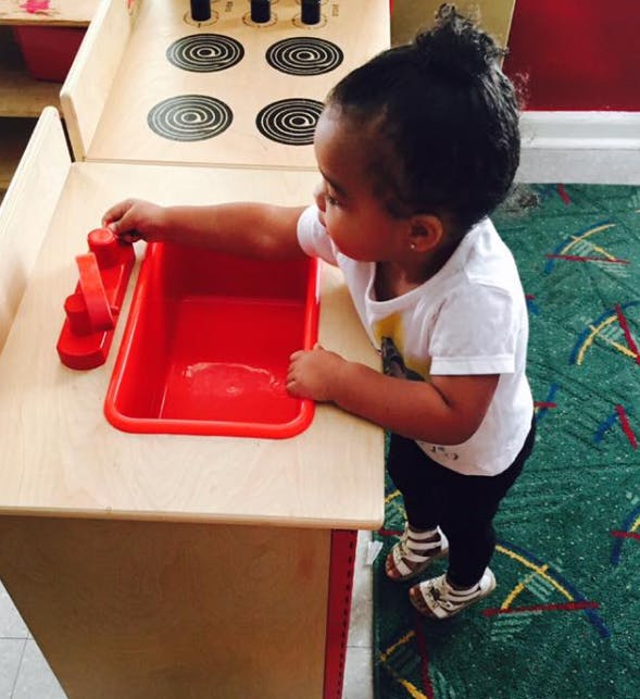 Child playing with a toy kitchen sink