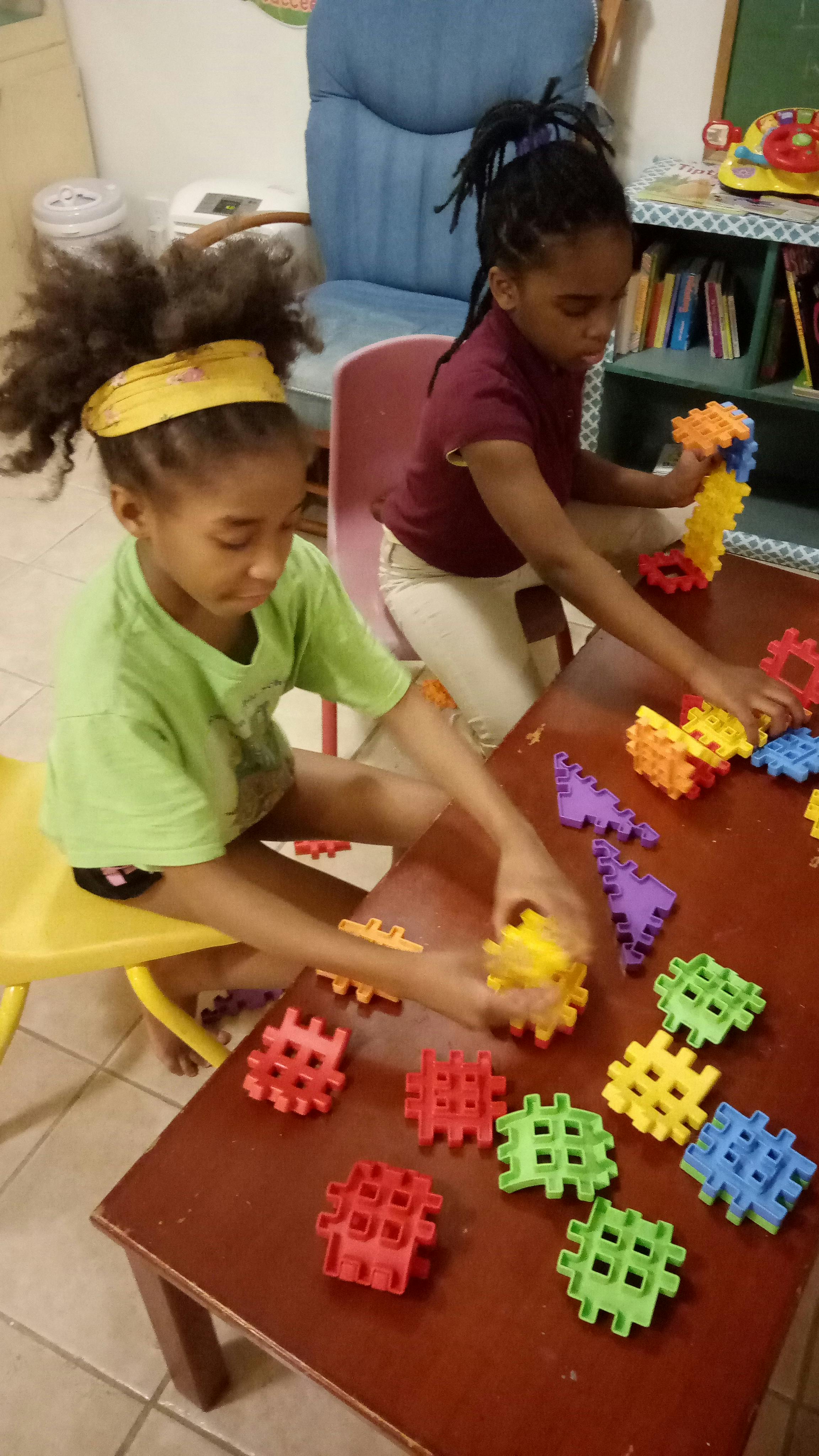 Two children playing with colorful interlocking building blocks at a table