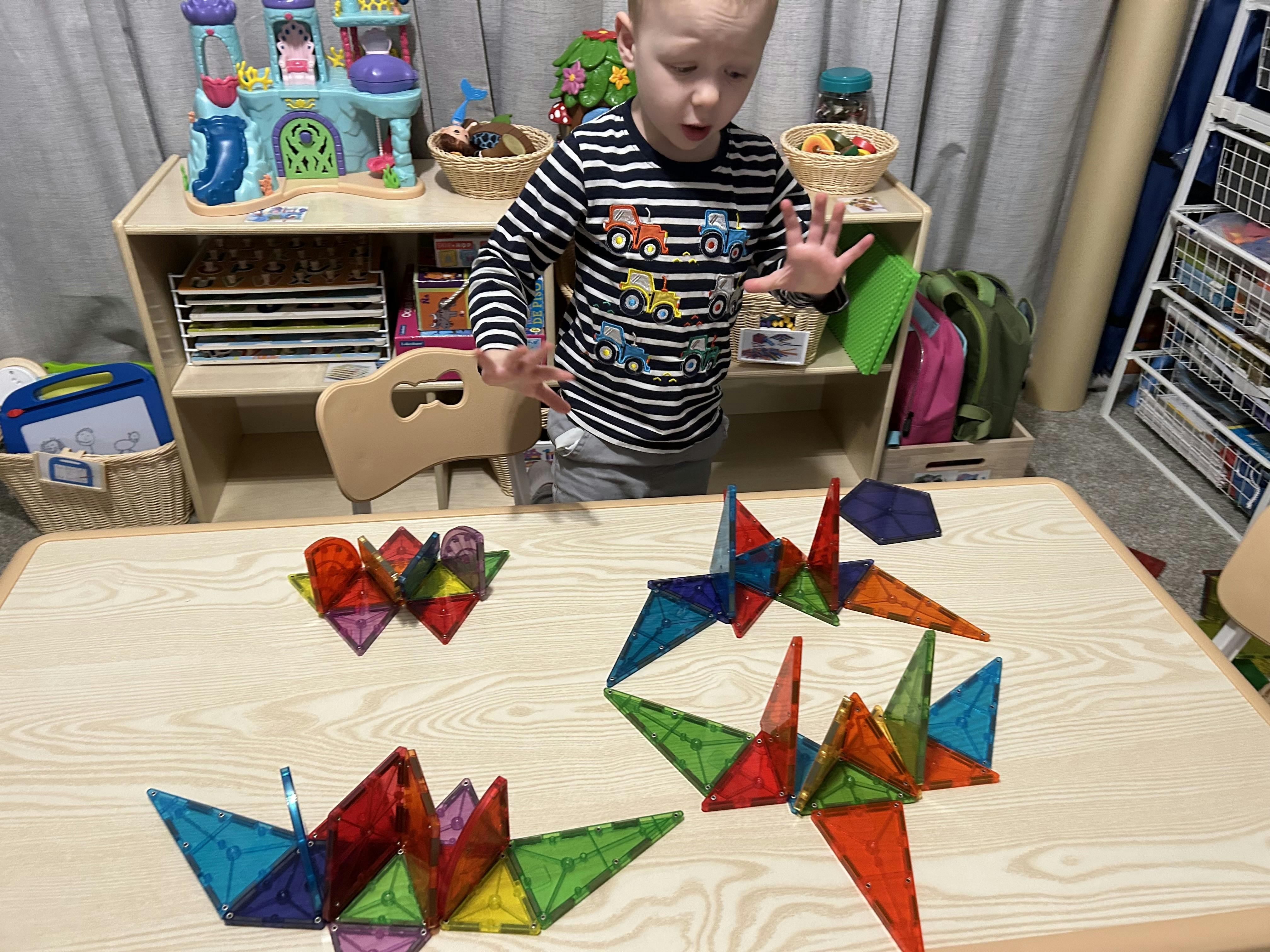 Child building with colorful magnetic tiles on a table